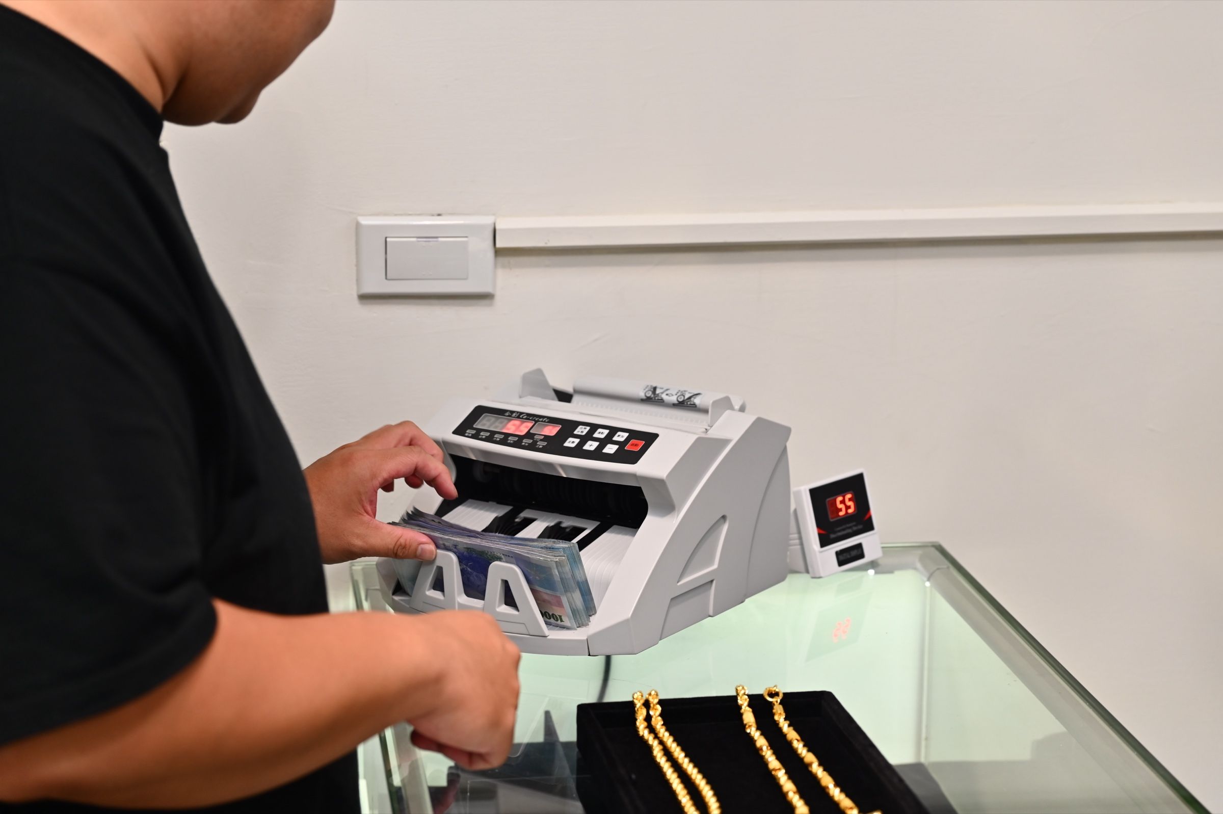 店內點鈔機運作中,顯示器亮著金額
